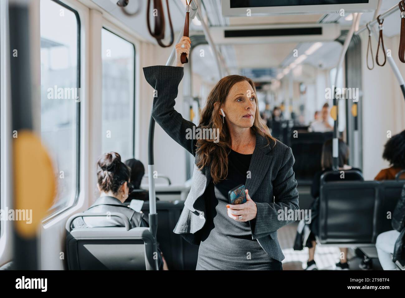 Weibliche Pendlerin, die ihr Smartphone im Zug hält Stockfoto