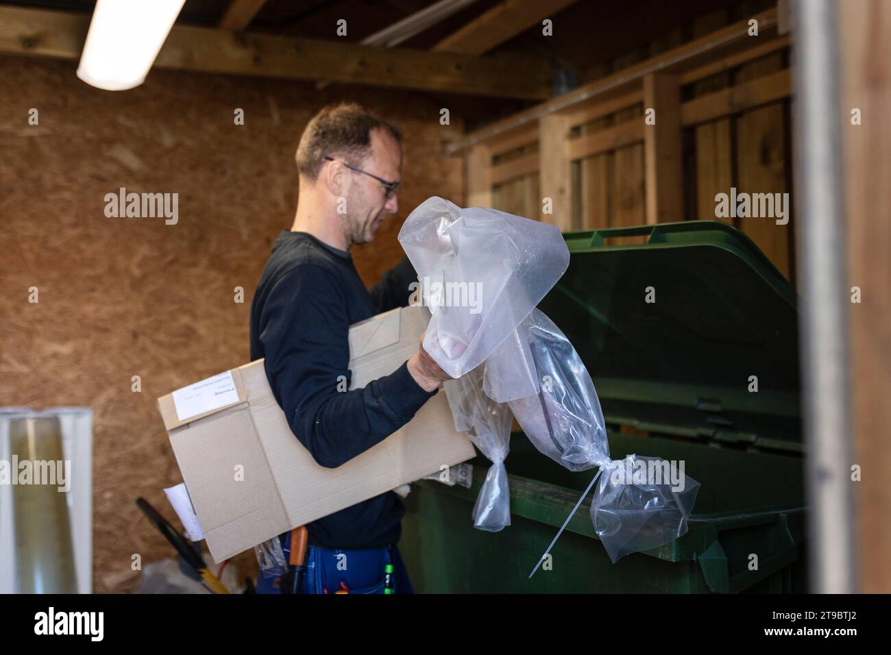 Seitenansicht eines männlichen Arbeiter, der Kunststoff- und Pappabfälle in den Mülltonnen wirft Stockfoto