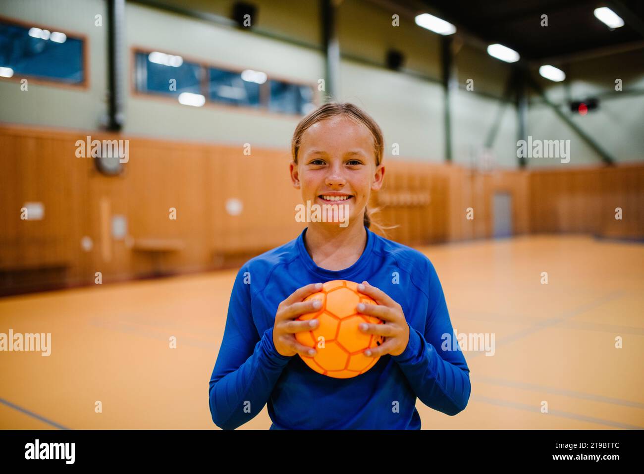 Porträt eines lächelnden Mädchens mit Handball auf dem Sportplatz Stockfoto