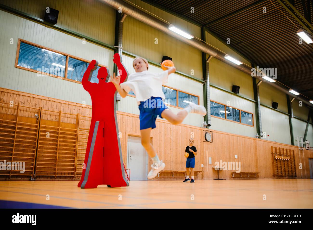 Handballspielerin springt beim Werfen von Handball auf dem Sportplatz Stockfoto