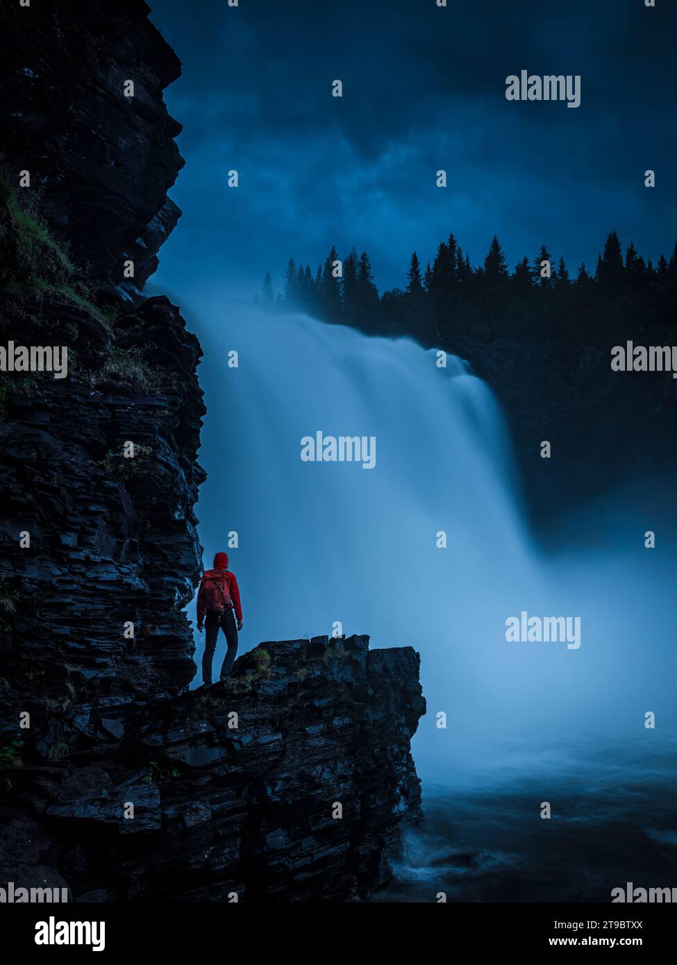 Wanderer, der den Tannforsen-Wasserfall ansieht, während er auf Felsen gegen den Himmel steht Stockfoto