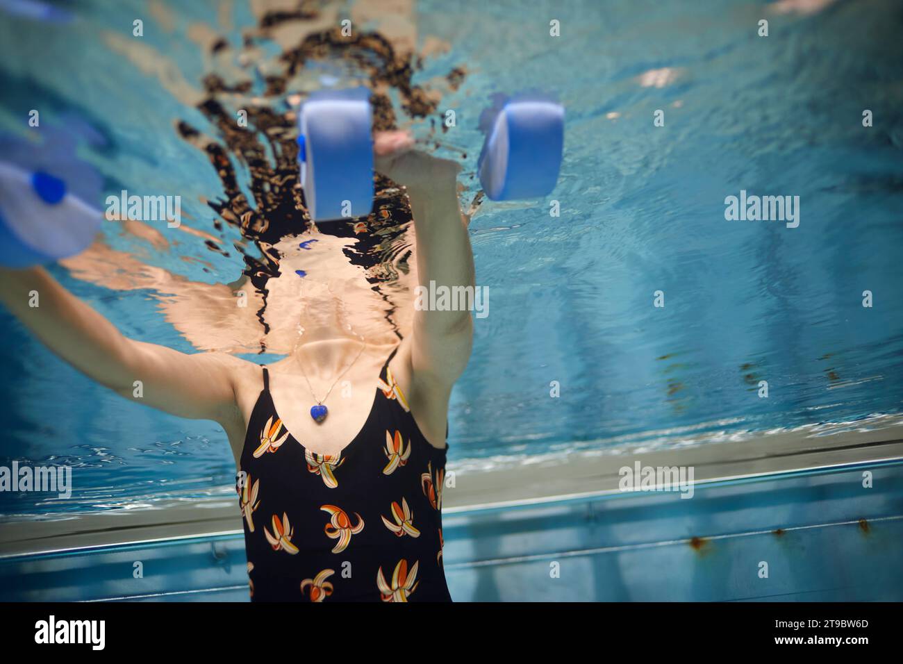 Mittelteil der Frau, die mit Kurzhanteln im Schwimmbad trainiert Stockfoto