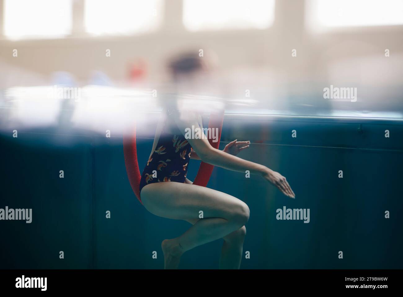 Seitenansicht einer Frau, die mit Nudelschwimmen im Schwimmbad trainiert Stockfoto