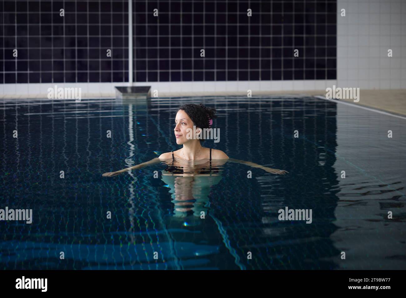 Reife Frau schwimmt im Schwimmbad im Rehabilitationszentrum Stockfoto
