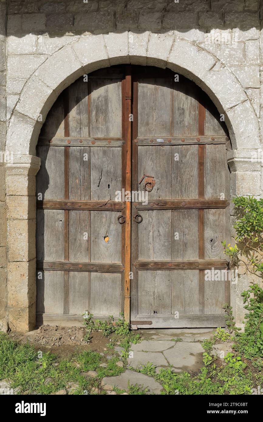 070 Alte farblose, zweiflügelige Holztür mit Rundbogen an Steinmauer, Rruga Kristaq Tutulani Straße, Gorica Viertel. Berat-Albanien. Stockfoto