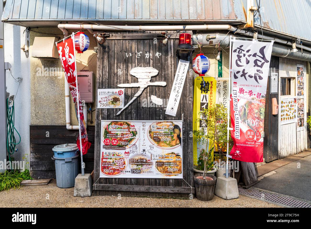 Typisch japanisches kleines Ramen Nudelbar Restaurant in Fukuyama, Japan. Banner und Menütafeln im Freien bieten verschiedene Preise. Stockfoto