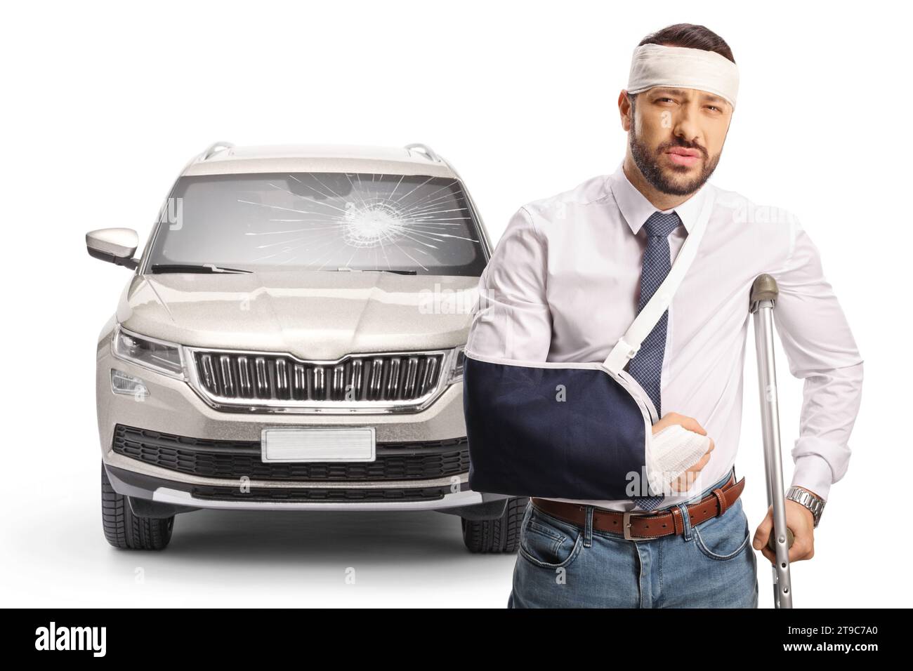 Verletzter Fahrer nach einem Autounfall, der mit einer Krücke vor einem Fahrzeug mit gebrochener Windschutzscheibe auf weißem Hintergrund steht Stockfoto
