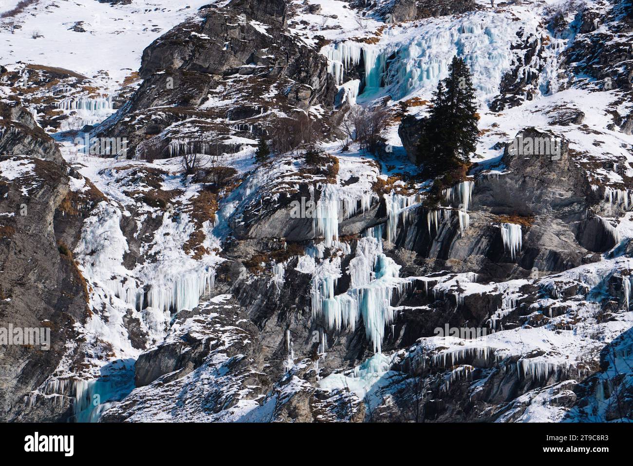 Eine gefrorene Landschaft in den französischen Alpen mit schneebedeckten felsigen Bergen mit markanten Eiszapfen, die ein winterliches Spektakel schaffen. Stockfoto