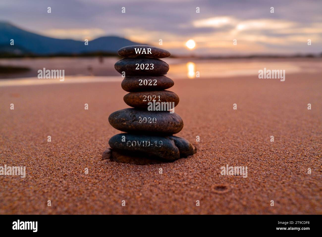 Ein frohes neues Jahr 2024 kommt mit einem großartigen Konzept und Design. Steinturm am Strand gestapelt Stockfoto