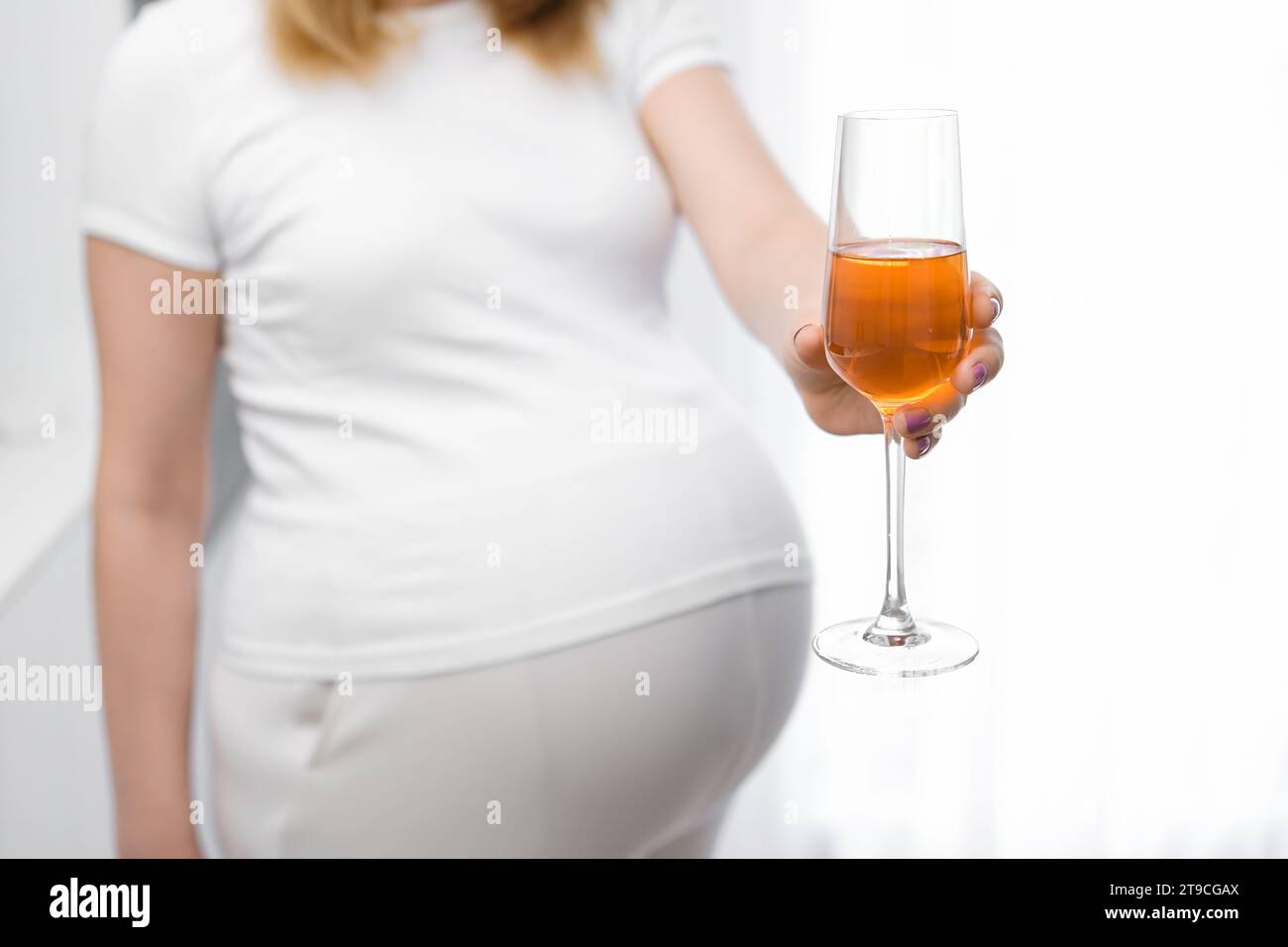 Schwangere Frau bietet ein Glas Wein an. Stockfoto