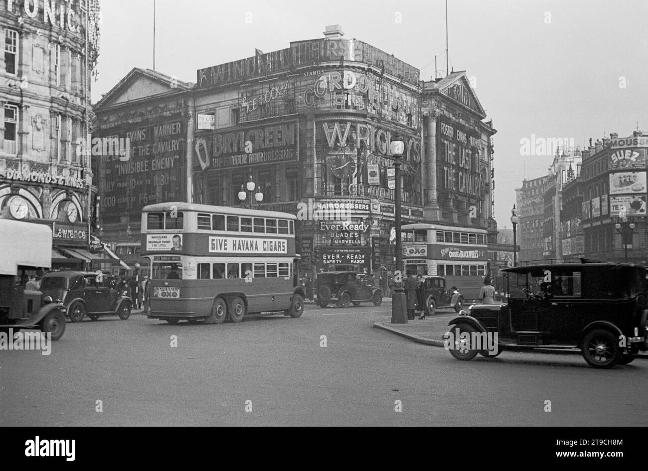 1938, historisch, Piccadilly Circus in dieser Ära, zeigt die Kreuzung der West End Road und Fahrzeuge des Tages, einschließlich eines London Taxi und Doppeldeckerbusse. An der Seite eines Busses eine Werbung für Havanna-Zigarren und eine für Maclean, mit Reginald Foort, einem Theaterorganist und einem populären BBC-Sender der 1930er und 40er Jahre Stockfoto