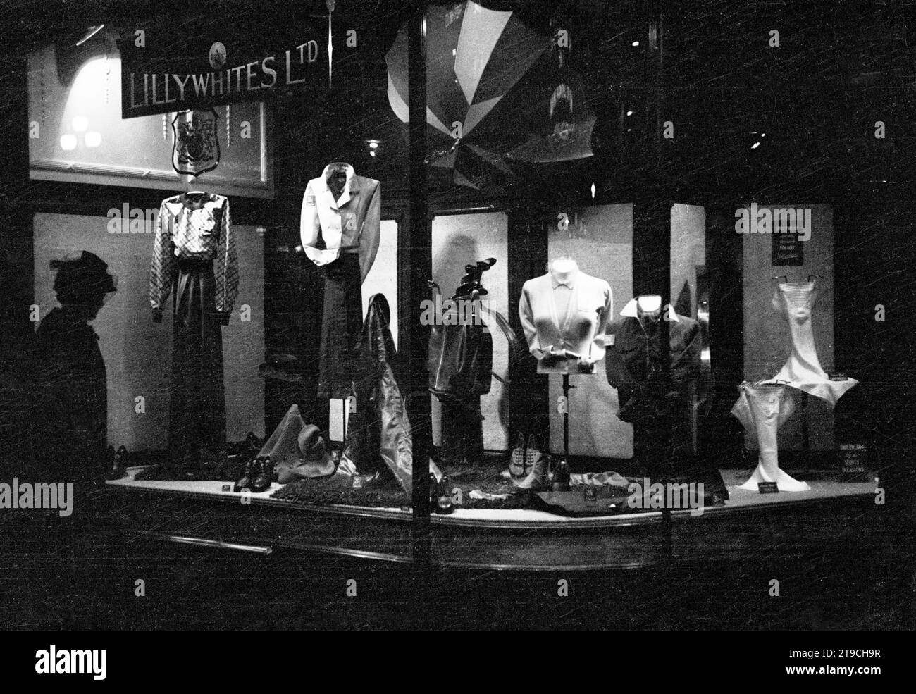 1940er Jahre, historisch, abends und eine Dame, die auf die Schaufenster des berühmten Sport- und Freizeitgeschäfts Lilllywhites im Piccadilly Circus im Londoner West End blickt. Stockfoto