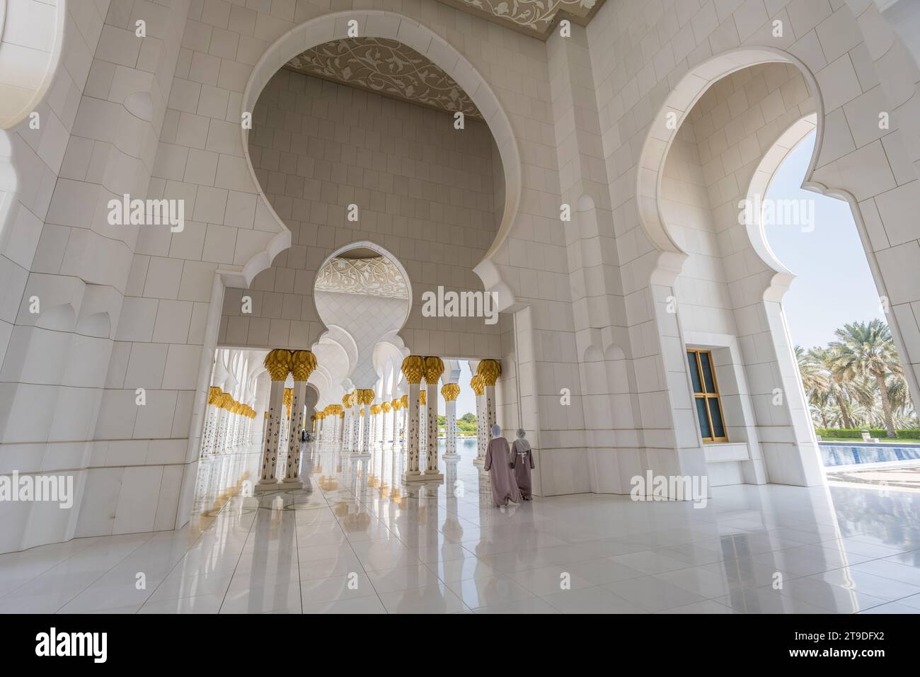 Abu Dhabi, Vereinigte Arabische Emirate - 8. Oktober 2023: Zwei Mädchen passieren den Säulenkorridor in der Scheich-Zayed-Moschee Stockfoto