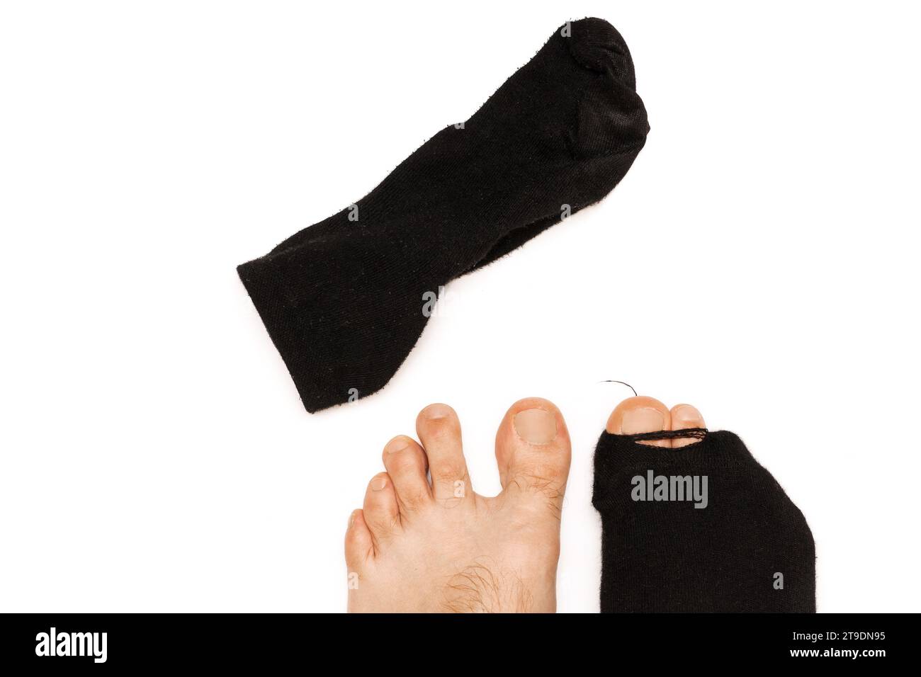 Nahaufnahme von männlichen Füßen mit einem Zehen aus einer schwarzen Socke auf weißem Hintergrund. Konzept von Armut und Finanzkrise. Stockfoto
