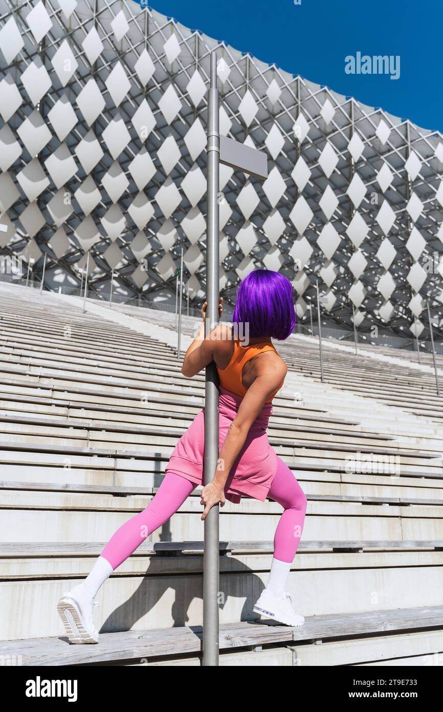Sorglose Tänzerin in farbenfroher Sportbekleidung, die an Sommertagen Spaß an der Pole hat Stockfoto