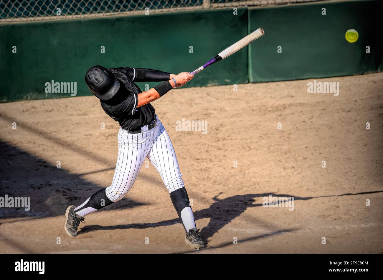 Ein Softball-Spieler schlägt und kommt mit dem Baseball in Kontakt Stockfoto