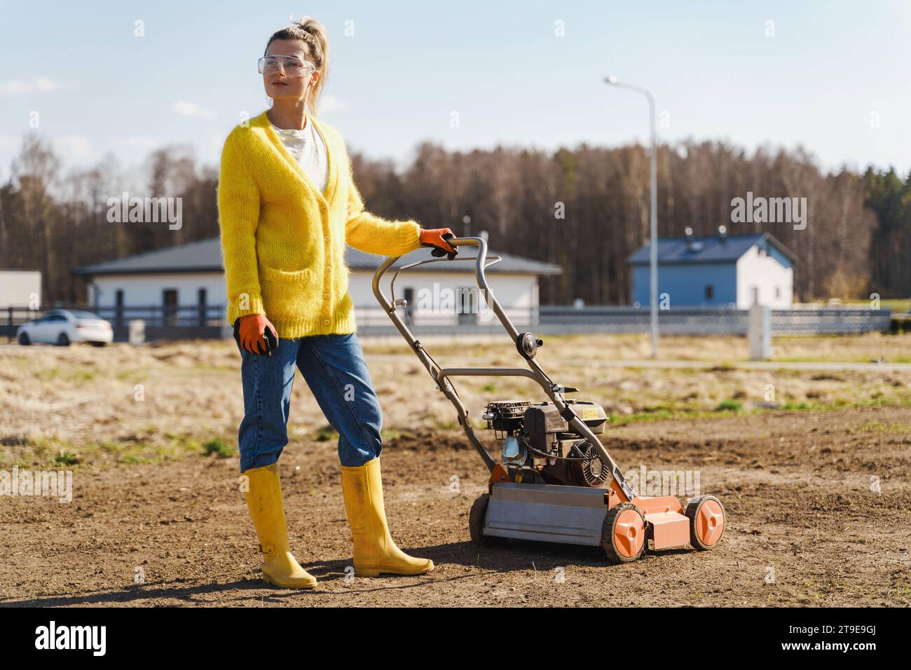 Junge Dorfbewohner benutzen Belüftungsmaschinen, um Rasen oder Wiesen zu verskarifizieren und zu belüften Stockfoto