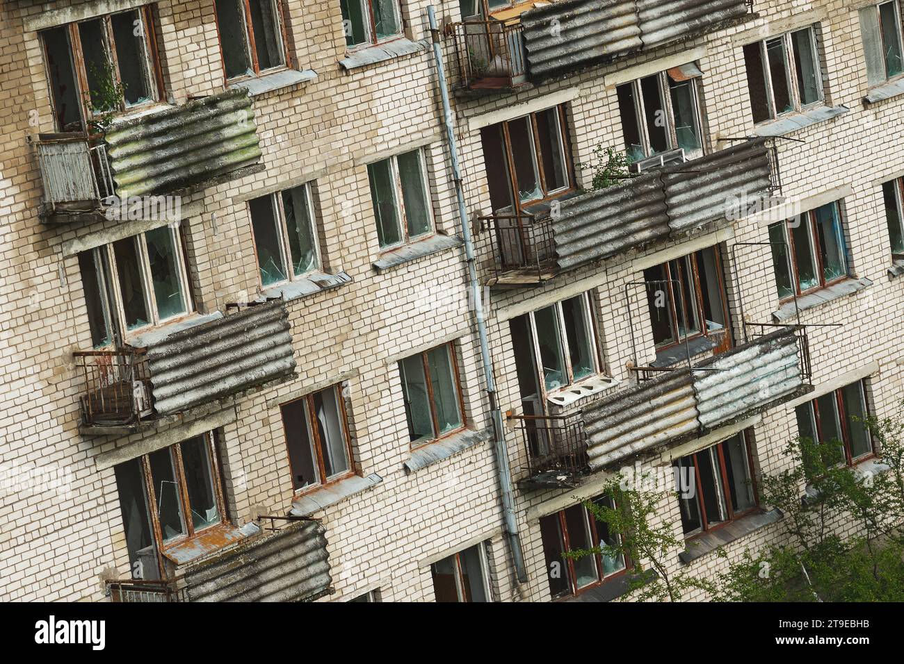 Außenansicht eines verlassenen Wohngebäudes mit kaputten Fenstern in einer einsamen europäischen Geisterstadt. Stockfoto
