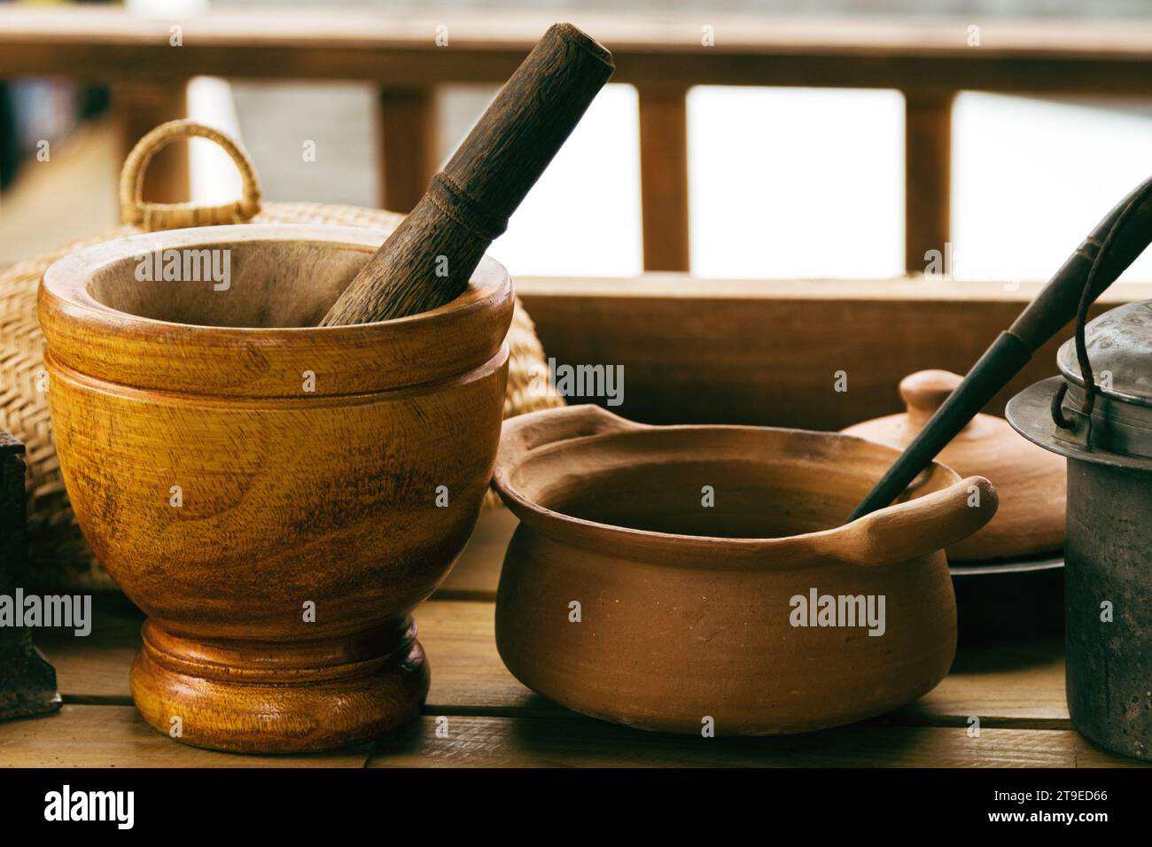 Nahaufnahme von handwerklich hergestelltem Mörtel, Stößel und anderem Küchengeschirr auf dem Holztisch im Landhaus. Stockfoto