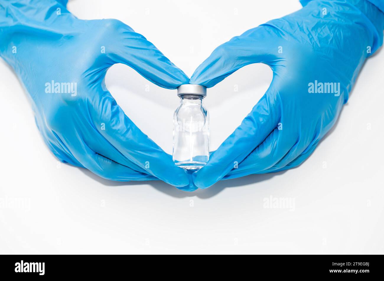 Hände in medizinischen Handschuhen halten Flasche mit Impfstoff oder flüssiges transparentes Arzneimittel, Konzept des Schutzes gegen neue Coronavirus-Infektion COVID-19 Stockfoto