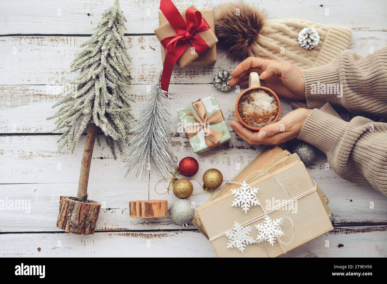 Frauenhände packen kleine Weihnachtsgeschenke und halten eine Tasse heißen Kaffees Stockfoto