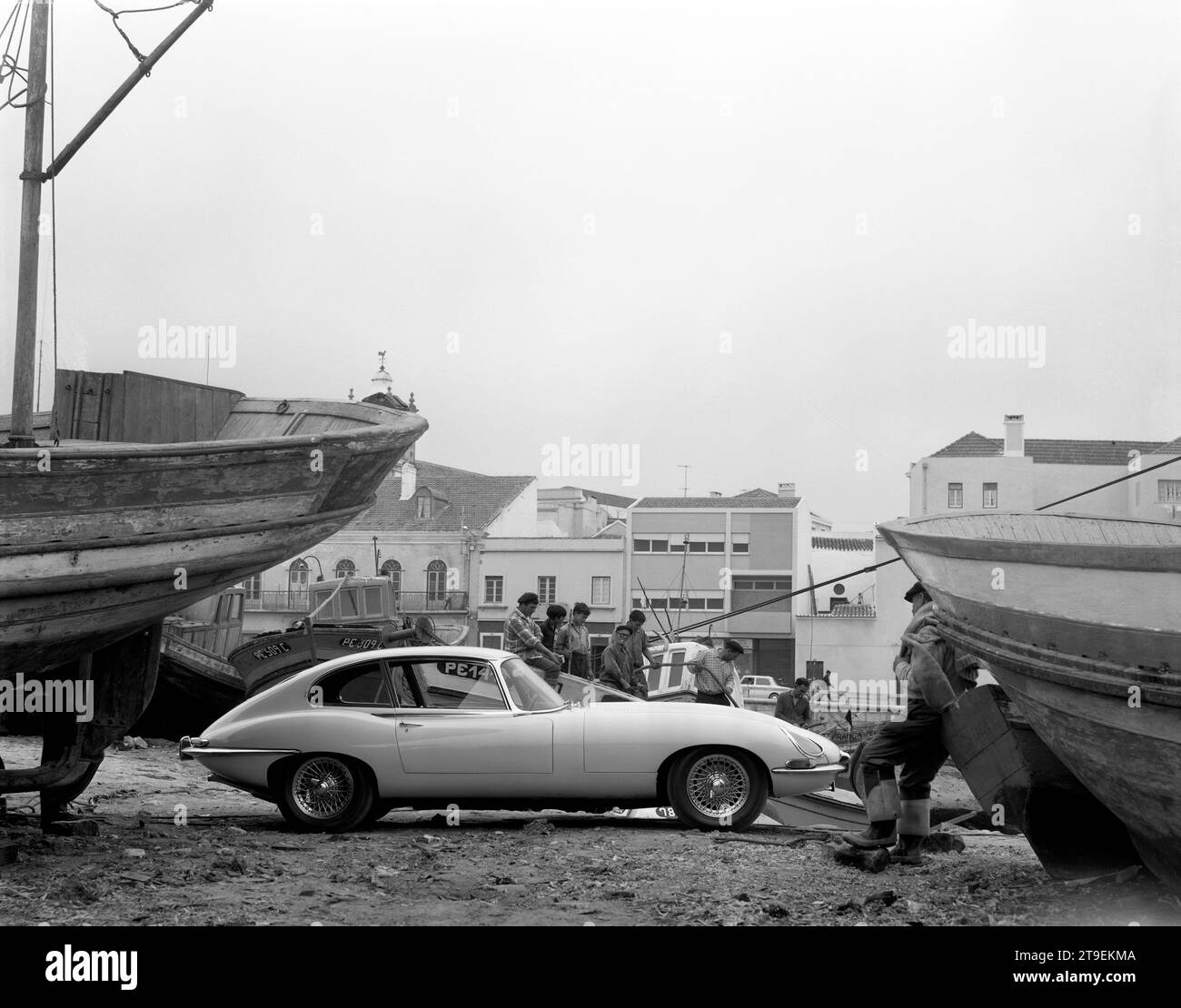 1966 Cream Jaguar E-TYPE, Serie 1, 2+2, im portugiesischen Hafen mit Fischerbooten und lackierten Häuserfronten und Fischern Stockfoto