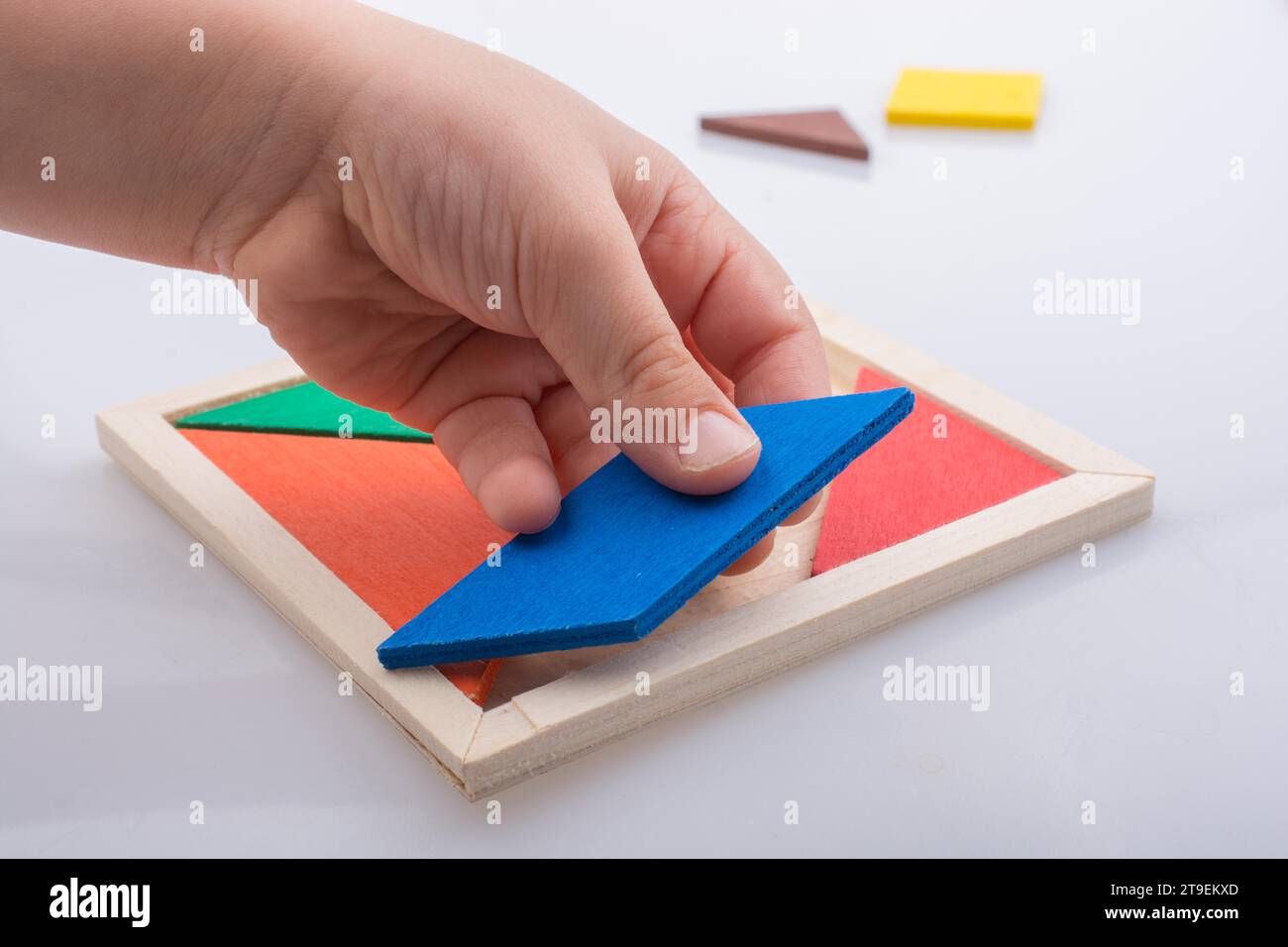 Hand hält ein fehlendes Stück in einem Tangram Puzzle Stockfoto