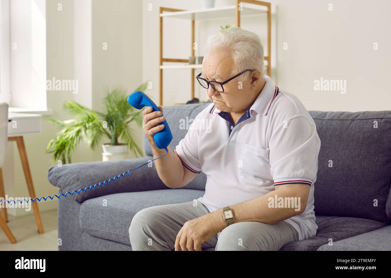 Dementierter Seniorenmann mit Alzheimer-Krankheit kann sich nicht erinnern, wie man das Telefon benutzt Stockfoto