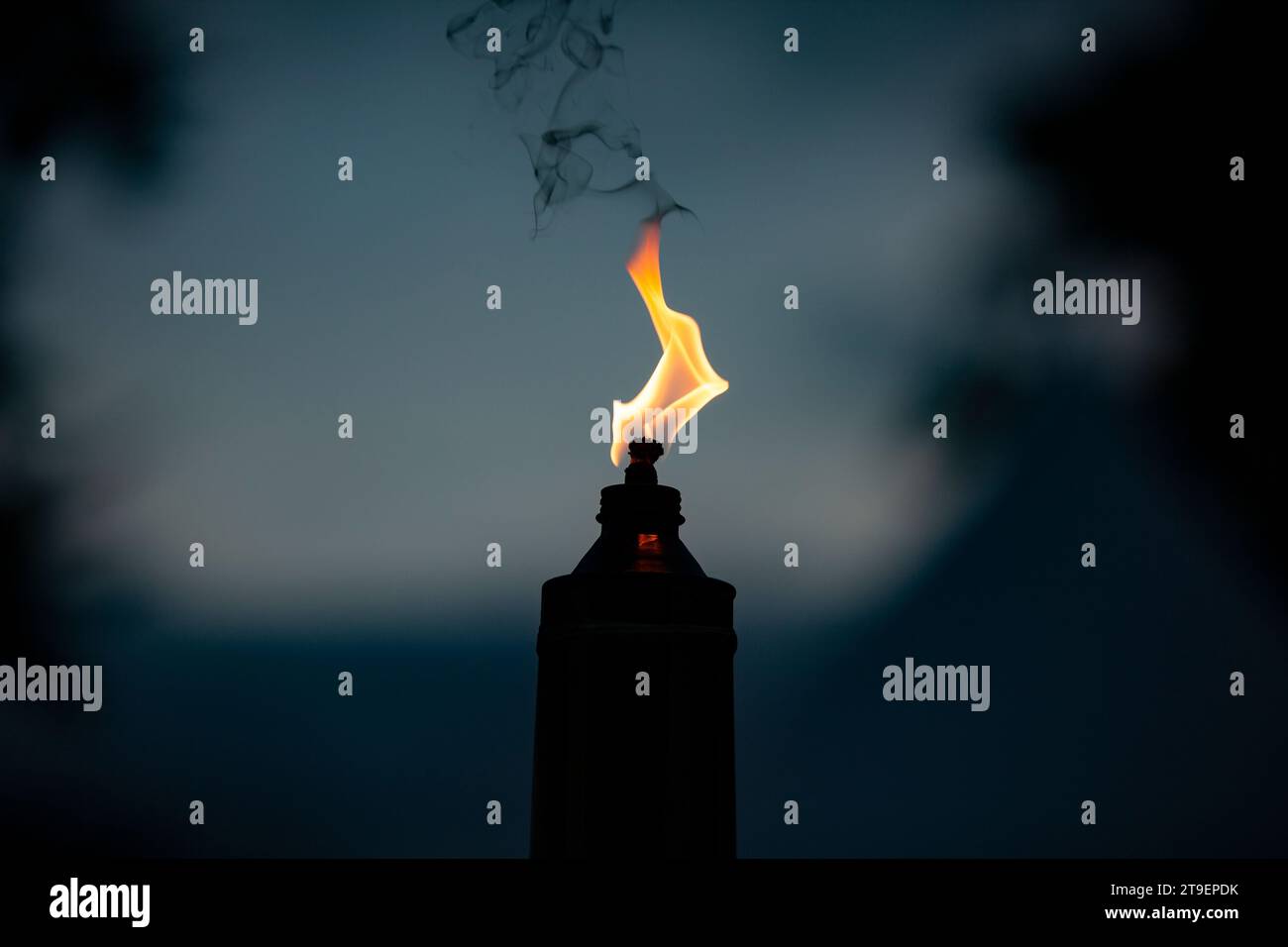 Flamme brennt orange aus einer einzelnen Kerzenlampe während der Nacht Stockfoto