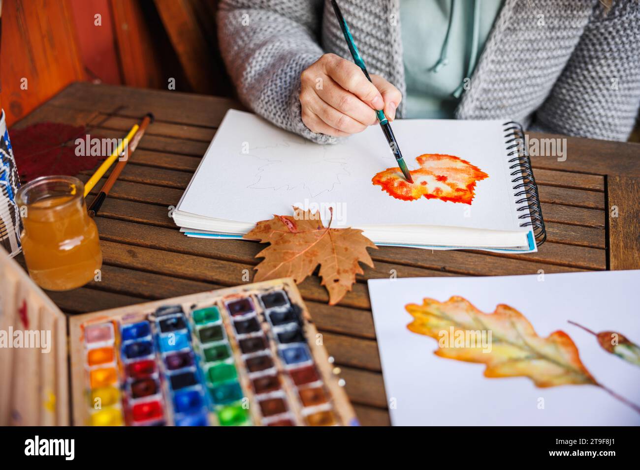 Aquarellmalerei. Eine Künstlerin malt ein Herbstmotiv auf Papier. Farbpalette in der Tabelle Stockfoto