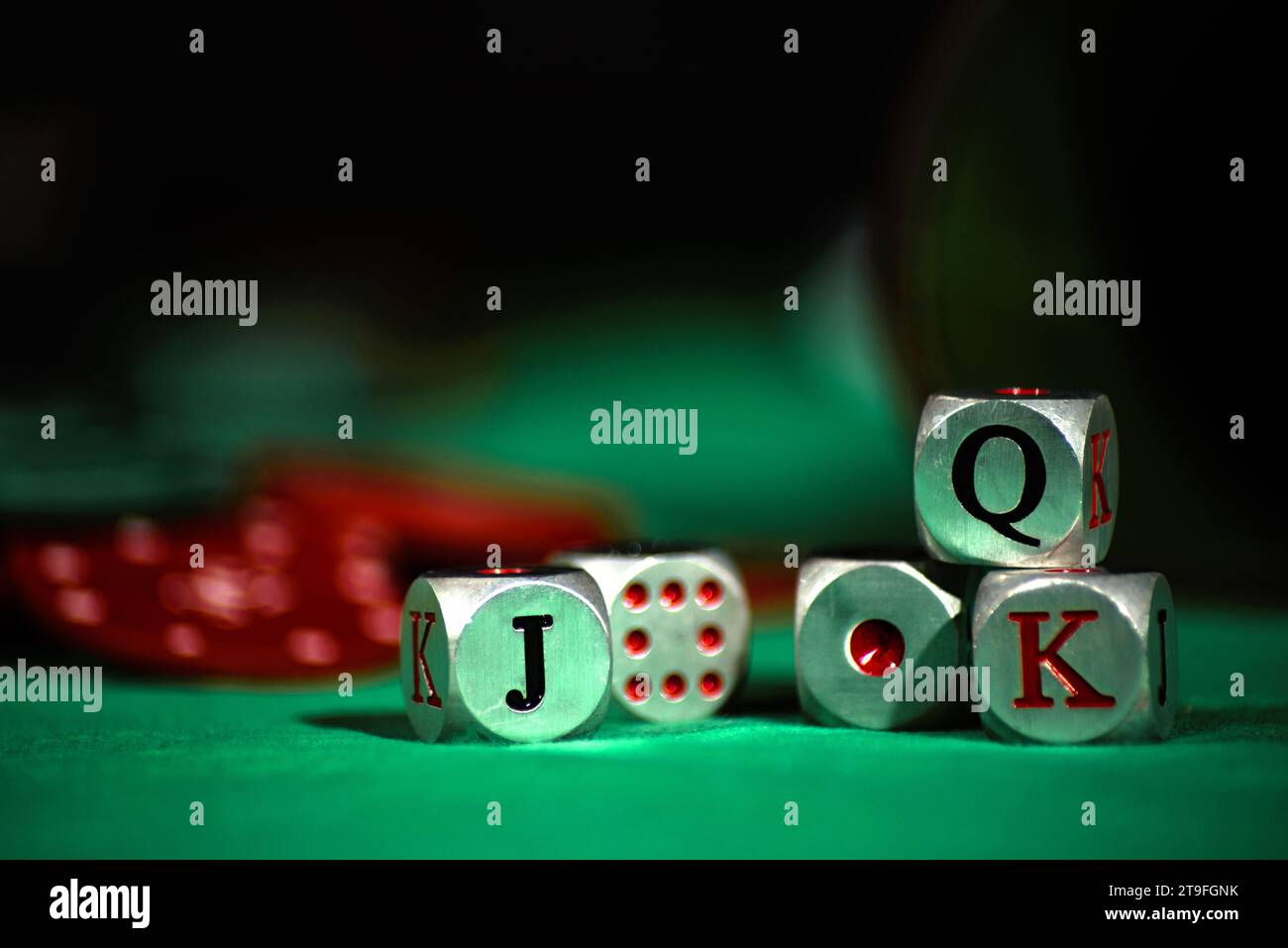 Tasse mit Pokerwürfeln auf einer grünen Matte mit roten Chips. Weckt die Emotionen von Spiel und Zufall. Selektiver Fokus. Stockfoto