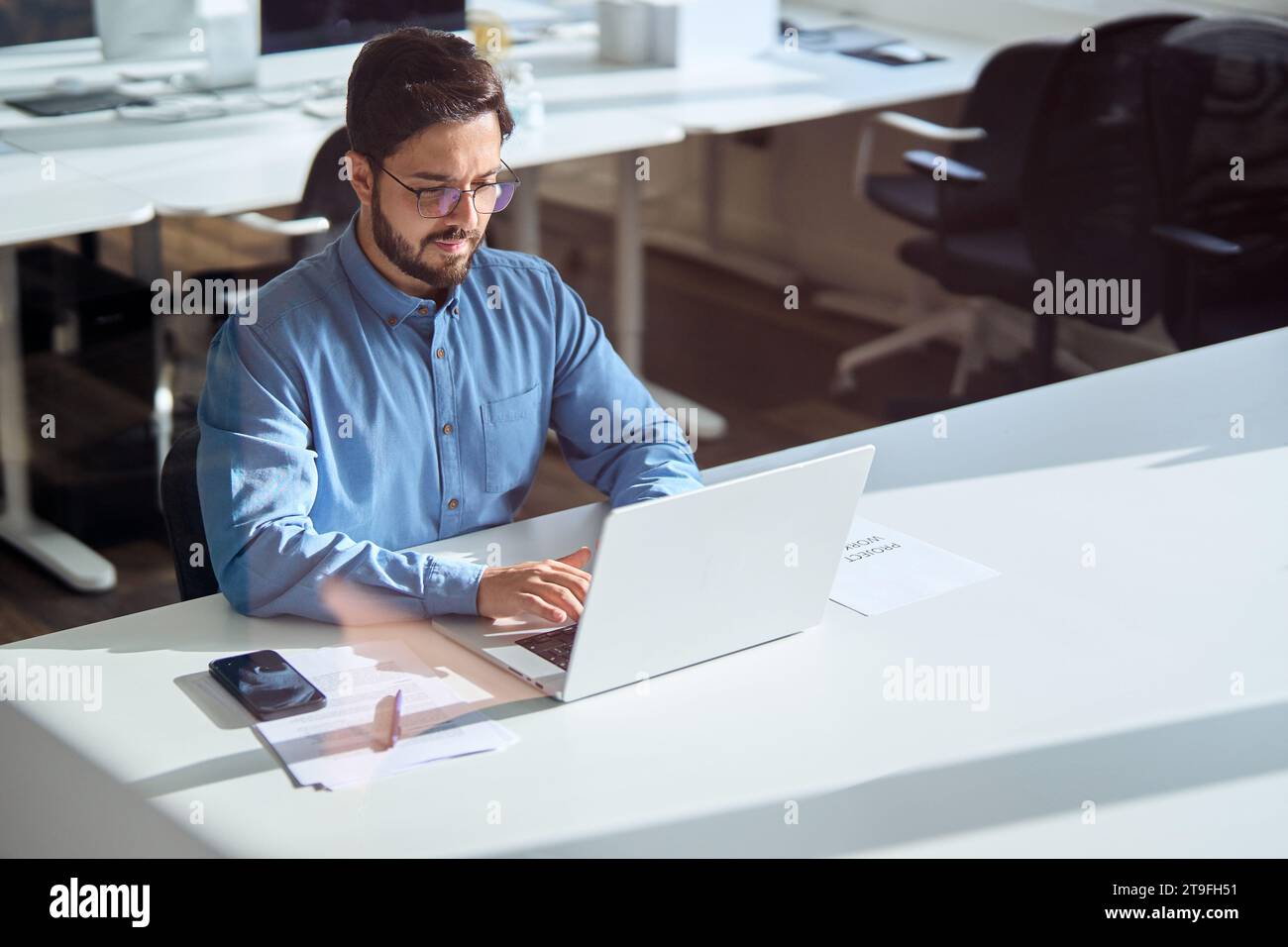 Geschäftiger Geschäftsmann aus lateinamerika, der im Büro einen Laptop benutzt. Stockfoto