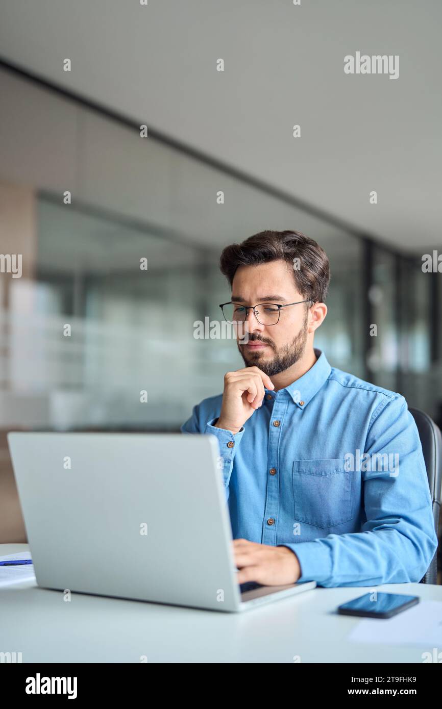 Ein geschäftiger Geschäftsmann, der im Büro an einem Notebook arbeitet. Vertikale Aufnahme. Stockfoto