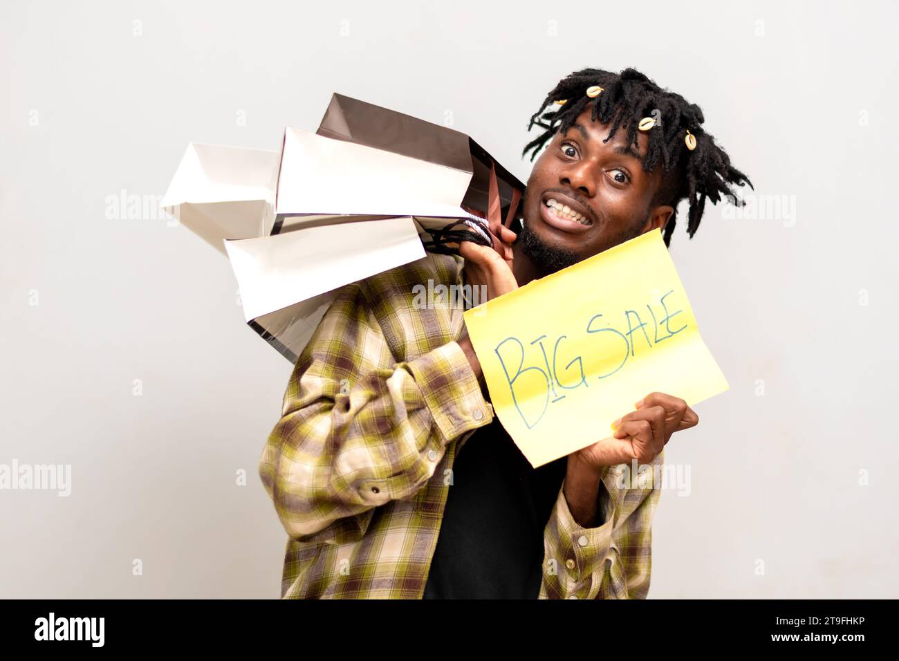 Afrikanischer Mann auf Dreadlocks mit Einkaufstasche und gelber Karte mit Big Sale-Aufschrift. Black Friday Stockfoto