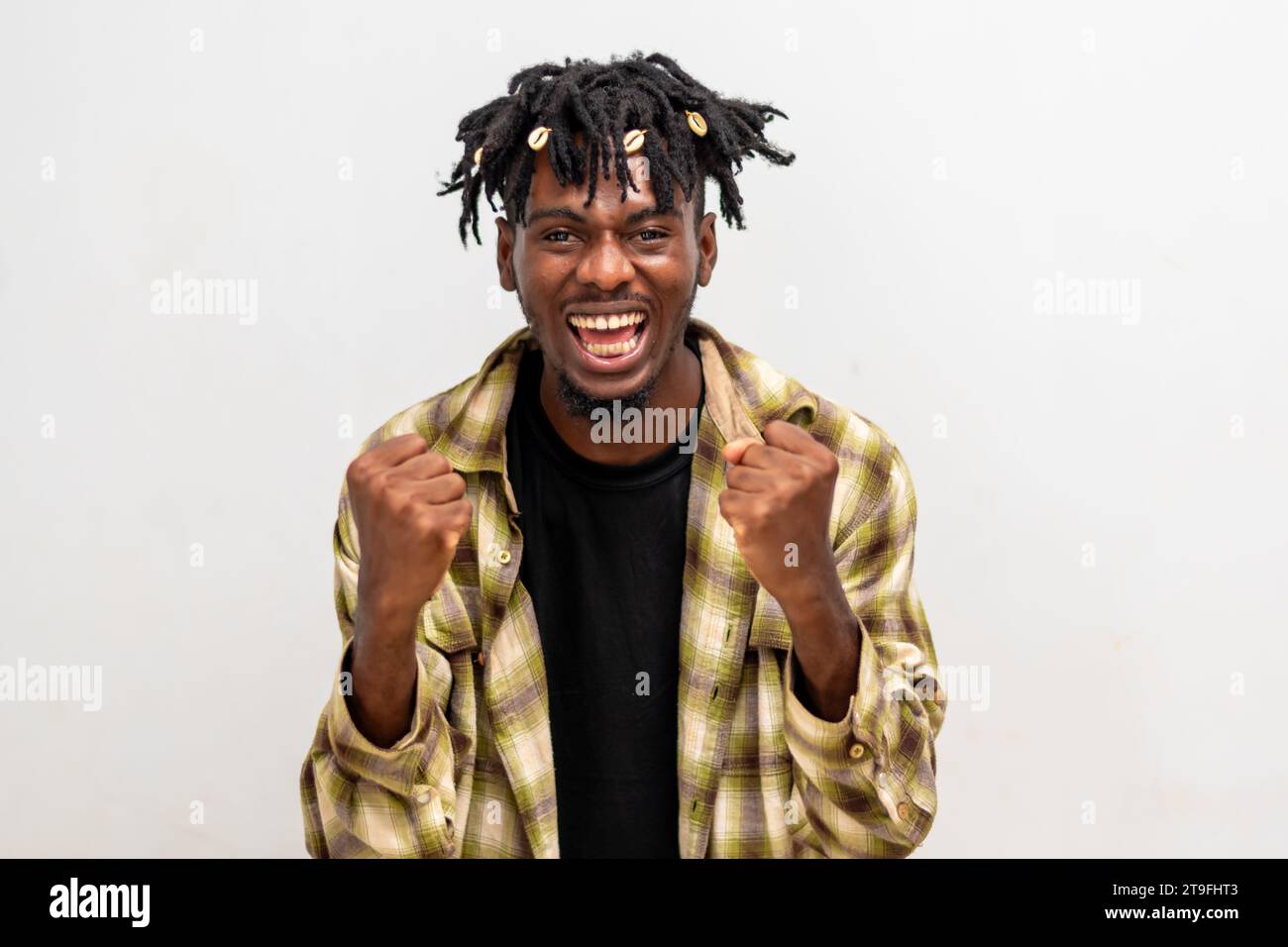 Aufgeregter junger Schwarzer auf Dreadlocks, der die Faust auf weißem Hintergrund hochhebt und Erfolg feiert. Glücklicher afrikanischer Millennial-Mann, der positive Gefühle teilt Stockfoto