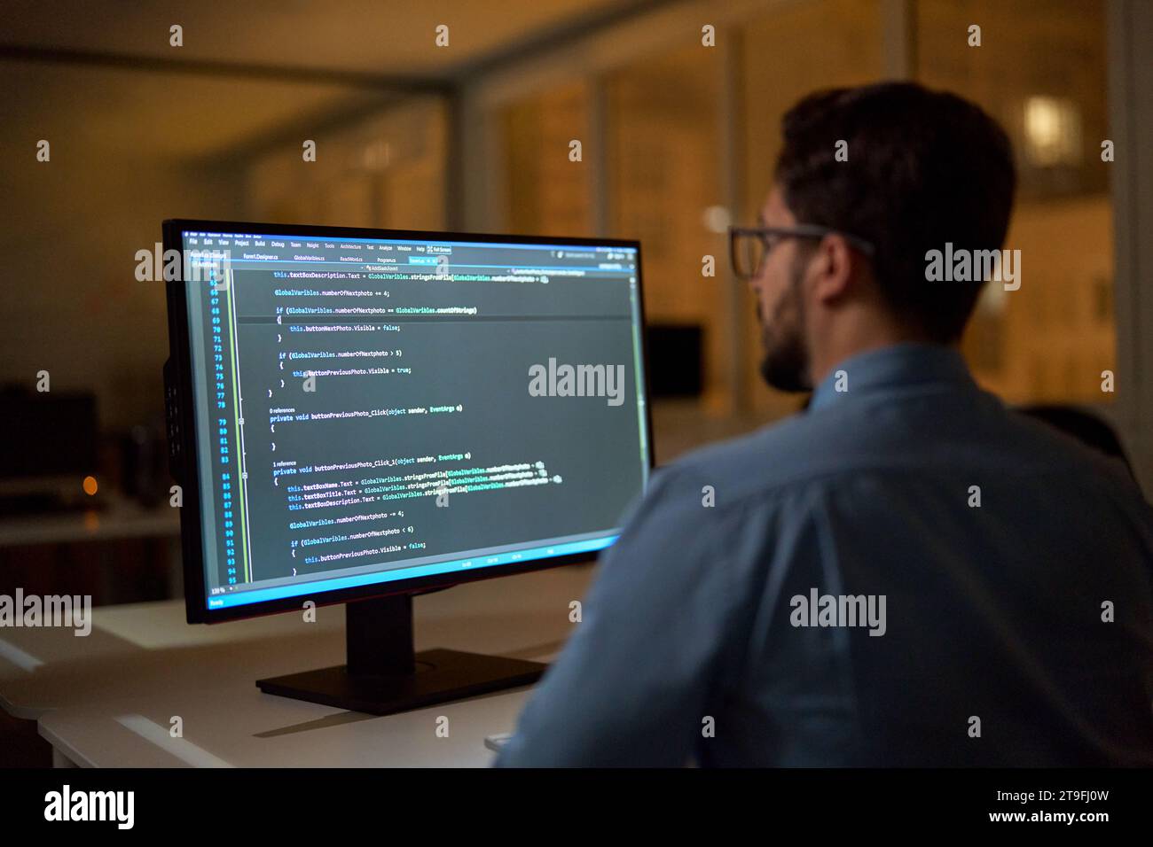 Geschäftlicher Softwareentwickler, der nachts im Büro am pc arbeitet. Stockfoto