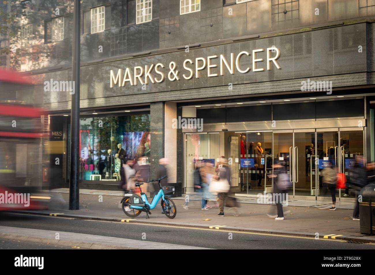 LONDON – 23. NOVEMBER 2023: Marks and Spencer Store and Motion verschwimmen die Käufer in der Oxford Street, einem Wahrzeichen des Einzelhandels Stockfoto