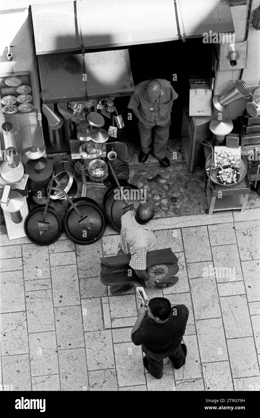 SARAJEVO BOSNIEN - MANN, DER MIT EINER WANDUHR VOR EINEM GESCHÄFT VORBEIGEHT - STRASSENFOTOGRAFIE - SILBERFILM © FOTOGRAFIE : FREDERIC BEAUMONT Stockfoto