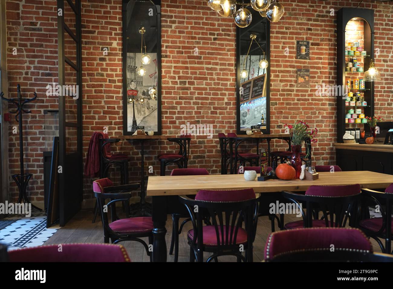 Rustikale Einrichtung des Restaurants mit Herbstdekor und Ambiente-Licht, rote Backsteinwand und Holztisch, elegante und warme, friedliche Einrichtung Stockfoto