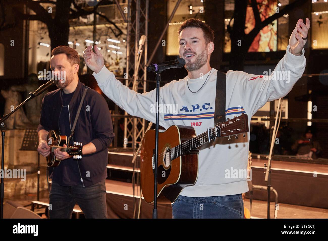 Hamburg, Deutschland. November 2023. Kris Hünecke (l), Gitarrist, und Johannes Strate, Sänger der Band Revolverheld, stehen auf einer Terrasse in der Mönckebergstraße und geben ein Überraschungskonzert. Quelle: Georg Wendt/dpa/Alamy Live News Stockfoto