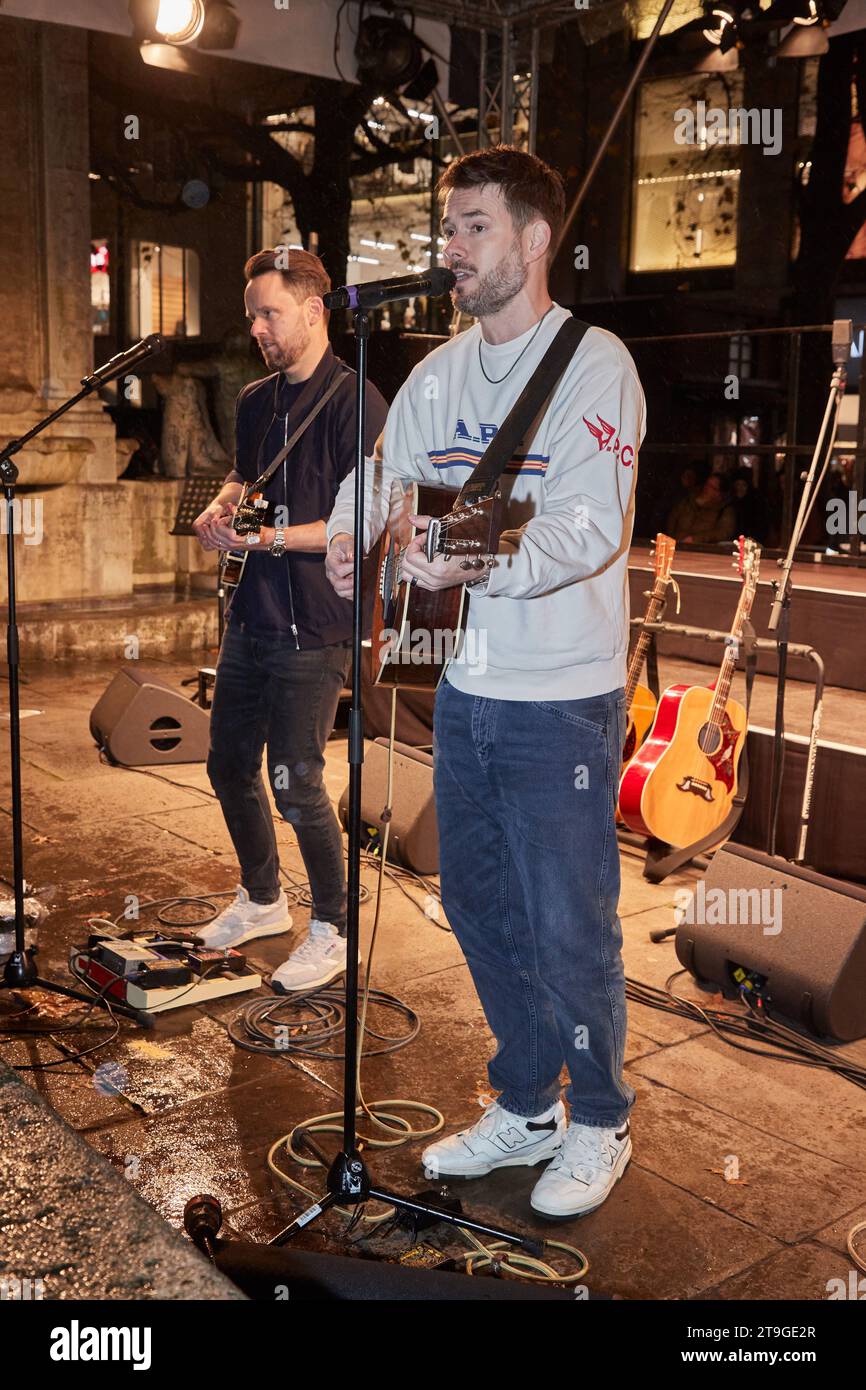 Hamburg, Deutschland. November 2023. Kris Hünecke (l), Gitarrist, und Johannes Strate, Sänger der Band Revolverheld, stehen auf einer Terrasse in der Mönckebergstraße und geben ein Überraschungskonzert. Quelle: Georg Wendt/dpa/Alamy Live News Stockfoto