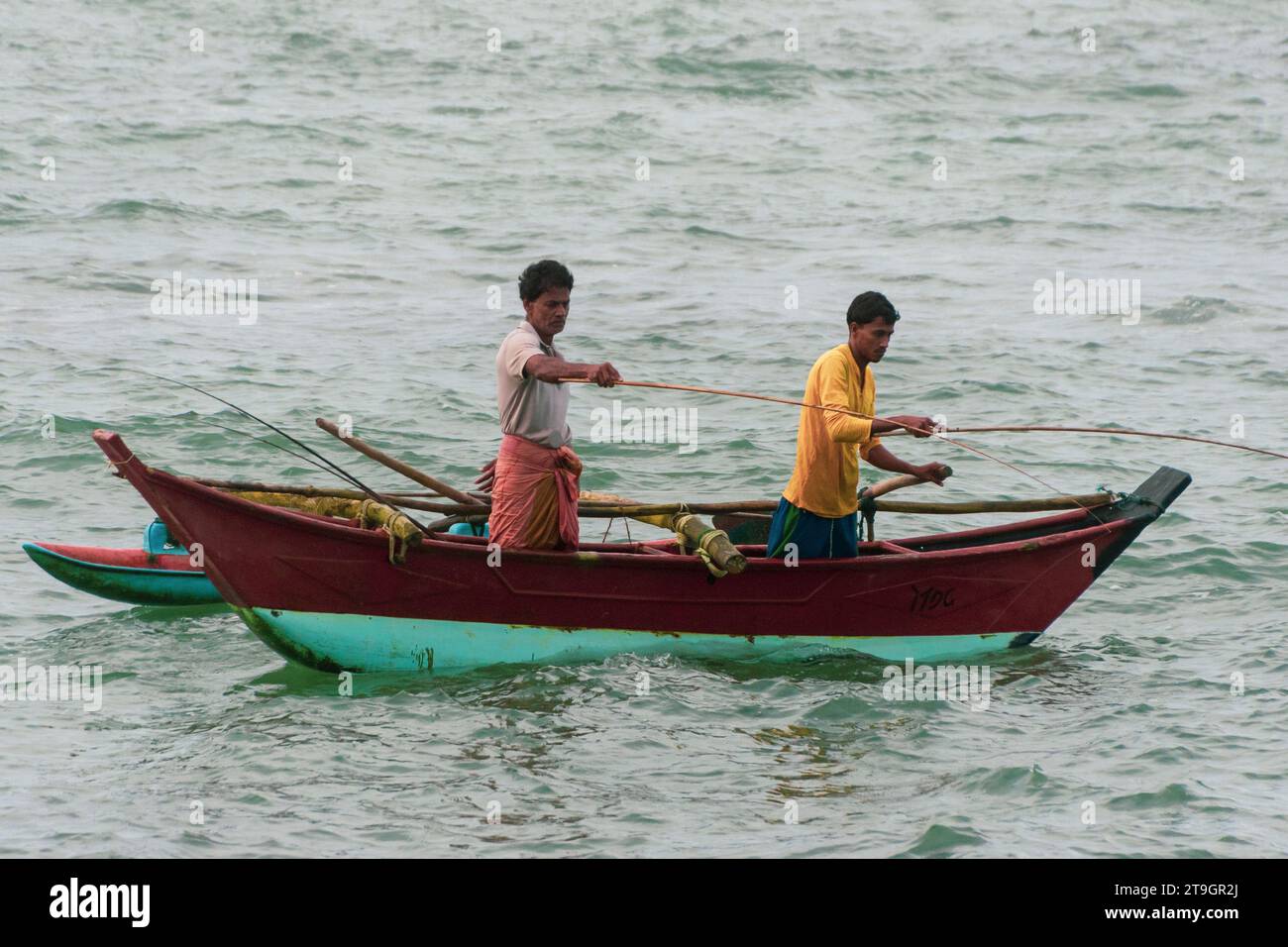 Zwei einheimische Fischer in einem Katamaranboot benutzen früh am Morgen in Mirissa Angelruten Stockfoto