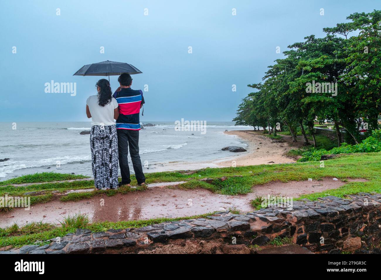 Ein Paar genießt den Blick auf den Strand von einem Sonnenschirm in Galle in Sri Lanka Stockfoto