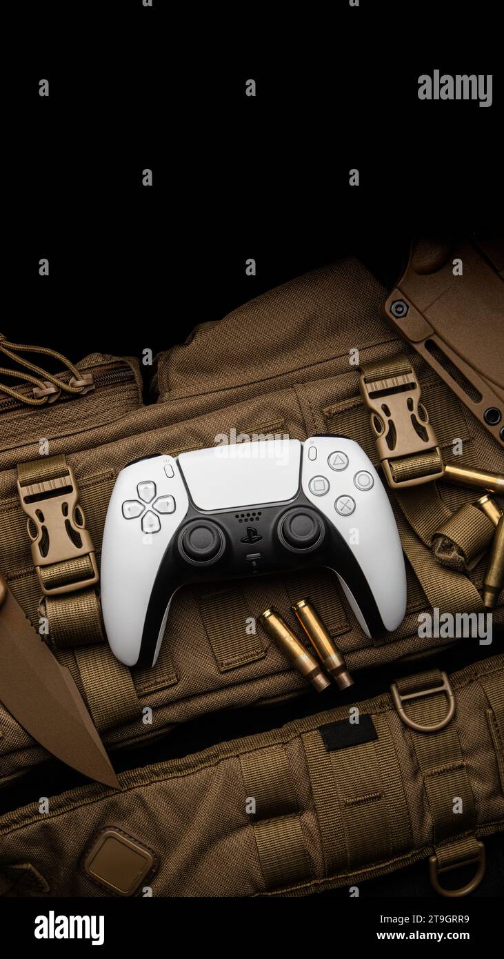 1. September 2021, Odessa, Ukraine. Weißer neuer Gamepad-Dualsense für PlayStation 5 auf einem modernen, wüstenfarbenen Militärrucksack. Militärische Messer und Muscheln Stockfoto