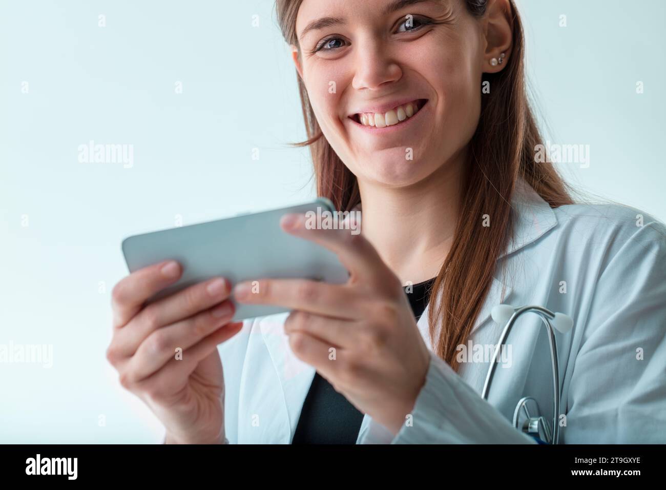 Ein optimistischer junger Mediziner wird mit einem Smartphone erfasst, was die dynamische und vernetzte Natur der modernen Medizin widerspiegelt Stockfoto