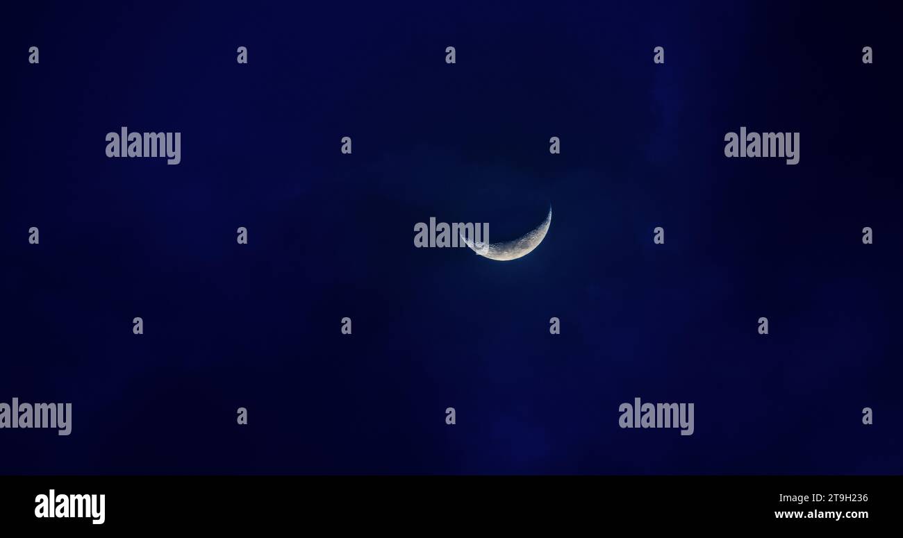 Mondsichel in Mitternachtsblau auf schwarzem Himmel in der Dämmerung. Stockfoto