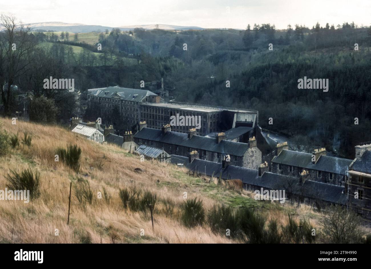 1977 Archivfoto der New Lanark Mill Welterbestätte in South Lanarkshire, Schottland. Das Unternehmen wurde 1785 von David Dale in Partnerschaft mit Richard Arkwright gegründet und war in einer Zeit der Partnerschaft mit Robert Owen erfolgreich und wurde erst 1968 geschlossen. Die utopischen Prinzipien der frühen Entwicklung als geplante Siedlung haben sie zu einem wichtigen Ort in der historischen Entwicklung der Stadtplanung gemacht. Es wird heute vom New Lanark Trust verwaltet und die Mühlen und das Dorf wurden als Touristenattraktion restauriert. Stockfoto