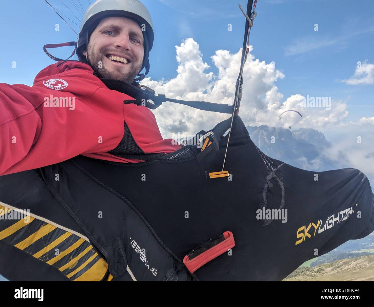 Paragliding Selfie, Selfie eines Paragliding Piloten, der hoch in den Wolken über Bergen mit seinem Gleitschirmflügel fliegt Stockfoto