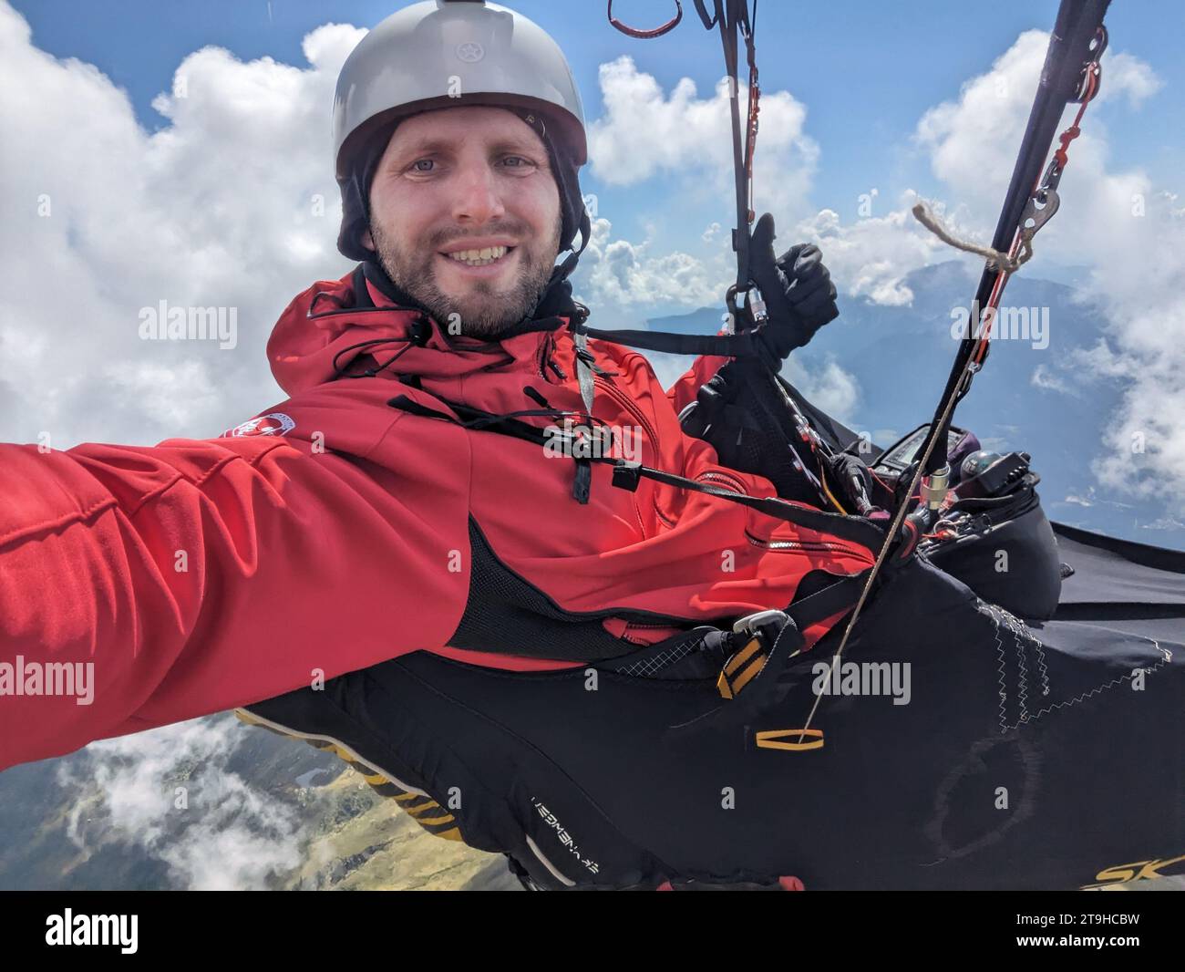 Paragliding Selfie, Selfie eines Paragliding Piloten, der hoch in den Wolken über Bergen mit seinem Gleitschirmflügel fliegt Stockfoto
