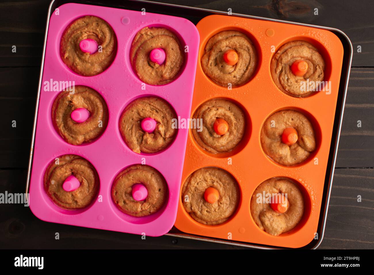 Gebackener Apfelwein Donut Teig in Silikon Donut Molds: Teig, der in Silikon Donut Formen in einer Blechform gegossen wurde Stockfoto